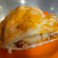 Slice of homemade apple pie with a flaky golden crust served on an orange plate.