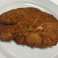 Breaded chicken cutlet prepared for chicken parmesan.