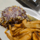 Chili cheese burger featuring a thick beef patty topped with rich beef chili and melted cheddar cheese on a toasted bun.