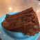 Slice of rich chocolate layer cake with chocolate frosting served on a blue plate.