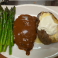 Chicken fried steak topped with country gravy, served with asparagus and a baked potato.