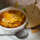 Cup of hearty tortilla soup topped with cheese and crispy tortilla strips served with a half sandwich.
