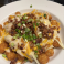 Loaded tater tots topped with melted cheese sauce, shredded cheese, bacon, and green onions.
