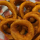 Basket of crispy golden onion rings served in checkered paper.