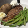 Grilled ribeye steak with green beans and baked potato with butter and sour cream.